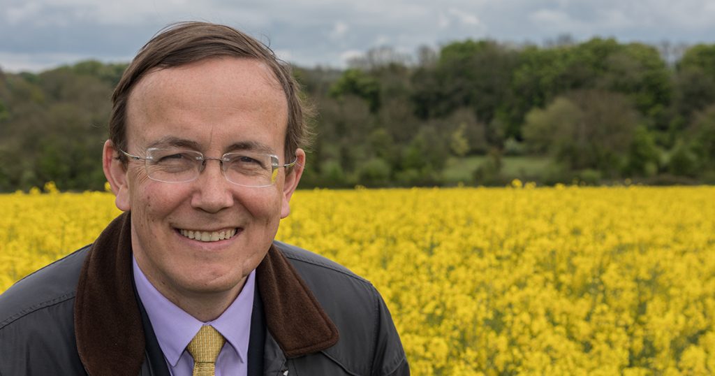 Portrait of Martin Tod in front of a field of yellow flowers